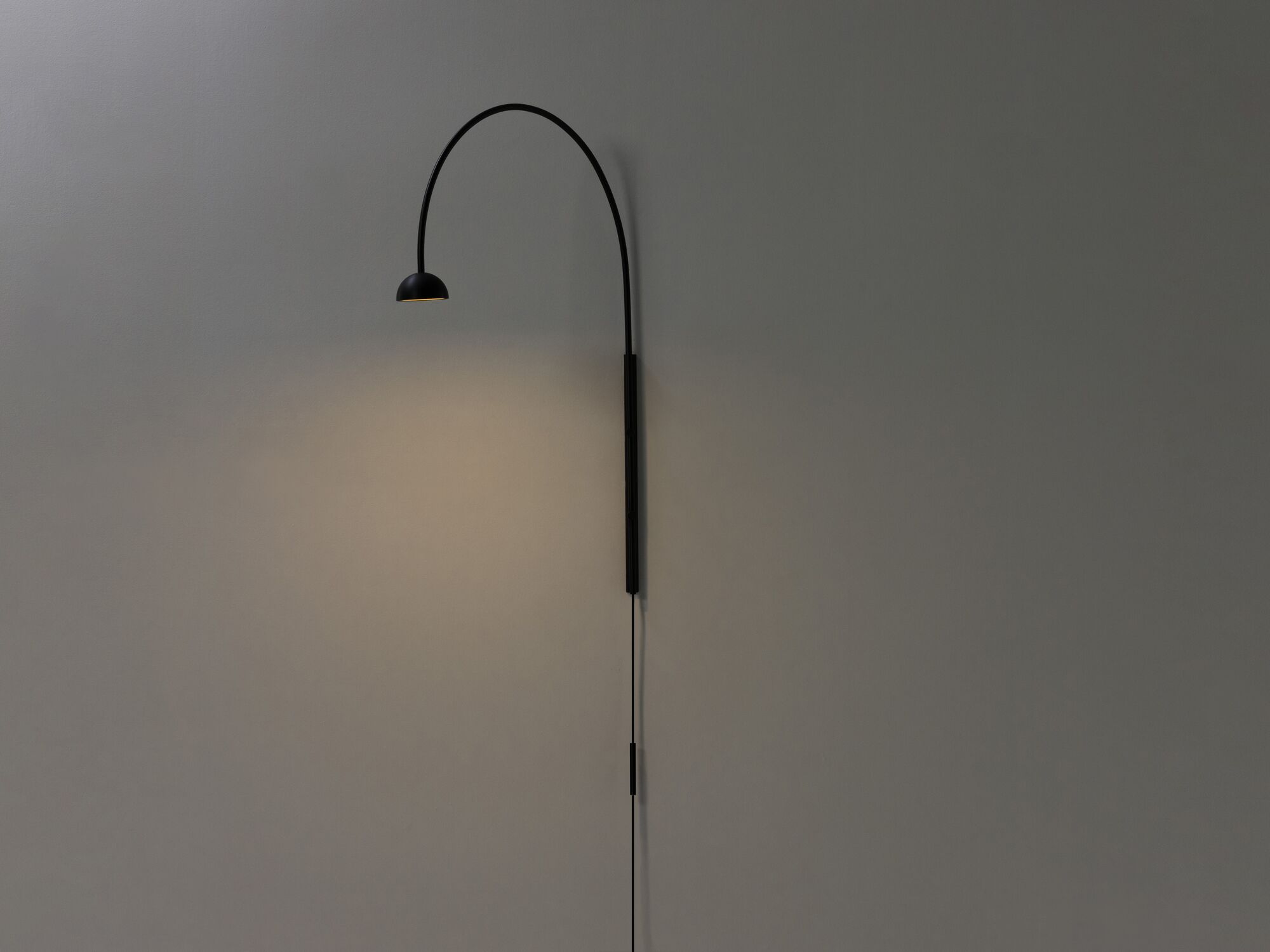 Black arched wall lamp with light on front angle view